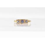 An 18ct yellow gold ring set with three sapphires and four tiny diamonds, size T, approx. 2.7g.