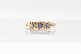 An 18ct yellow gold ring set with three sapphires and four tiny diamonds, size T, approx. 2.7g.