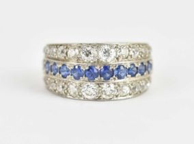 A white metal ring set with continuous row of twenty-five graduated sapphires flanked by rows of