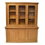 A large pine dresser/bookcase with glazed three-cupboard top, above a base of three fielded and