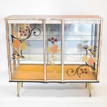A 1960s glass cocktail/display cabinet, with mirror back, two glass shelves, floral gilt decorated