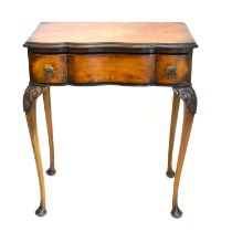 A reproduction walnut veneered lowboy with quarter-veneered top over shaped drawer, raised on