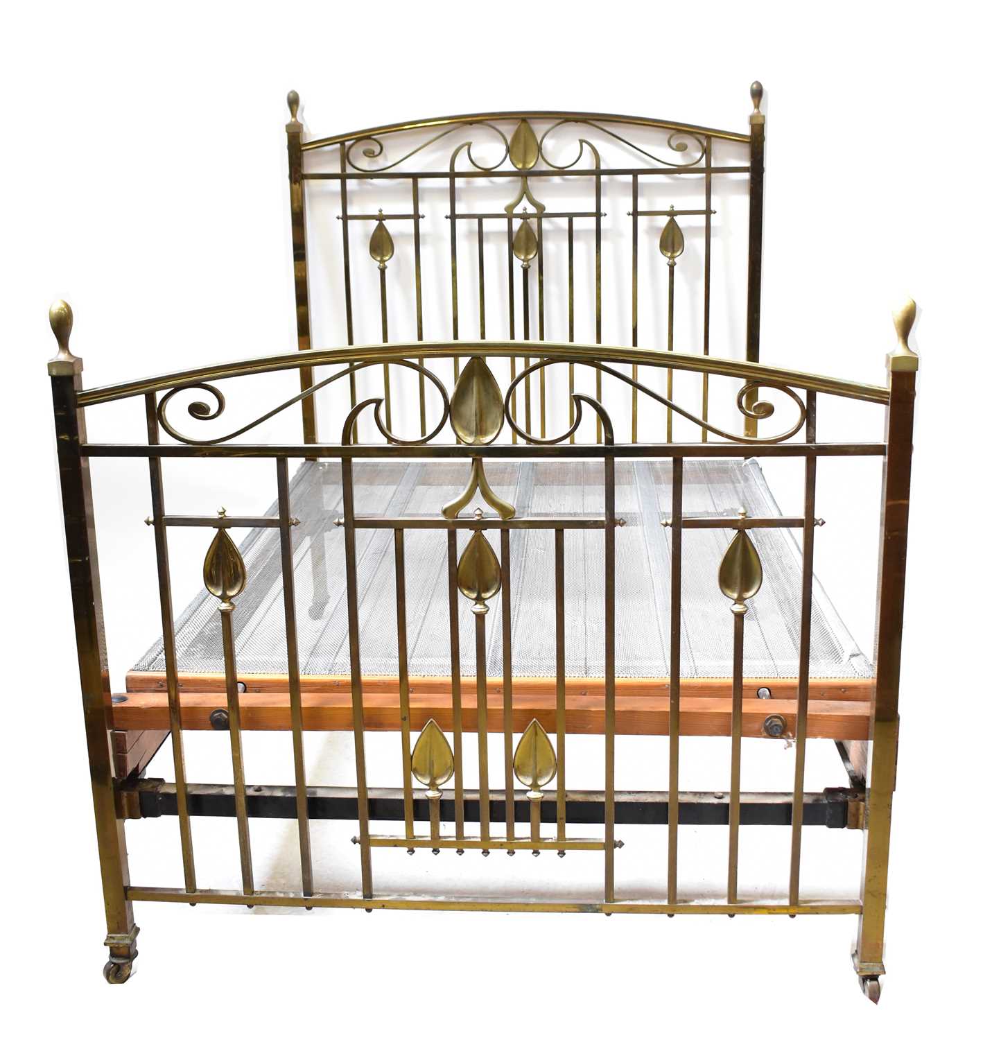 An Art Nouveau brass double bedstead with stylised leaf motifs, arched headboard and foot rail, to