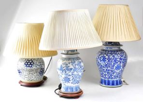Three Chinese blue and white table lamps in the form of Ginger jars, two on turned wooden bases,