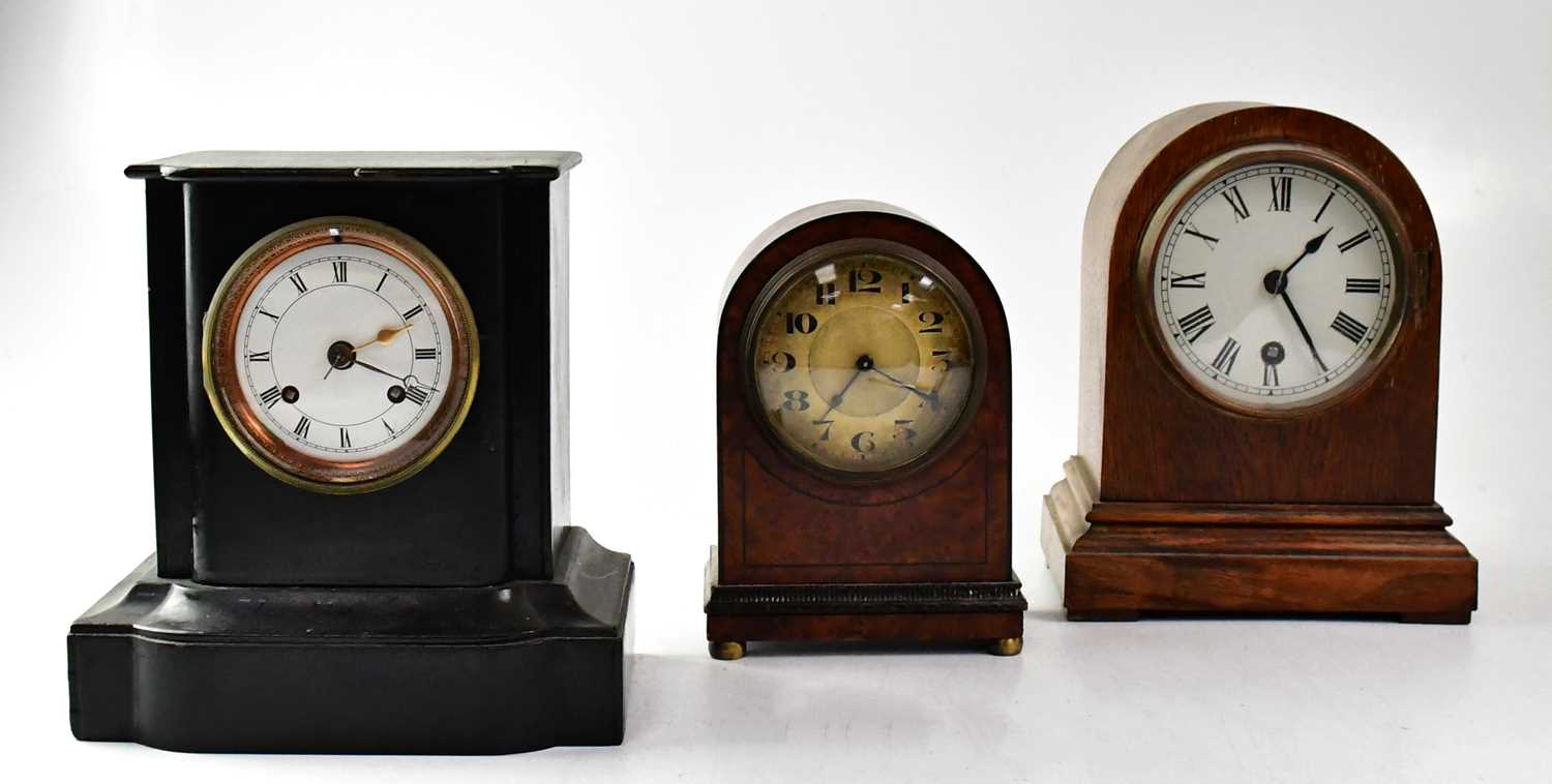 A Victorian slate-effect ebonised wooden mantel clock, together with an Edwardian oak arch-topped