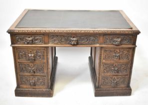 An early 20th century carved oak nine-drawer twin pedestal desk with leather inset panel to the top,