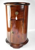 A 19th century style mahogany drum bedside table, with single drawer above cupboard door, on
