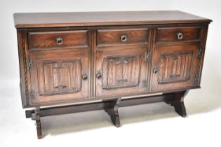 An early 20th century dark stained oak side cabinet with three frieze drawers above three panelled