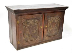 An 18th century oak cupboard top with blind carved floral doors, brass furnishing and interior