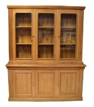 A large pine dresser/bookcase with glazed three-cupboard top, above a base of three fielded and