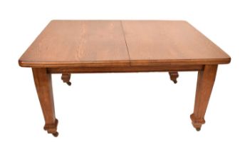 A large early 20th century oak wind-out table with three additional leaves, raised on substantial