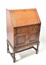 A mid-20th century oak student bureau with fall-front above a single drawer with fielded and