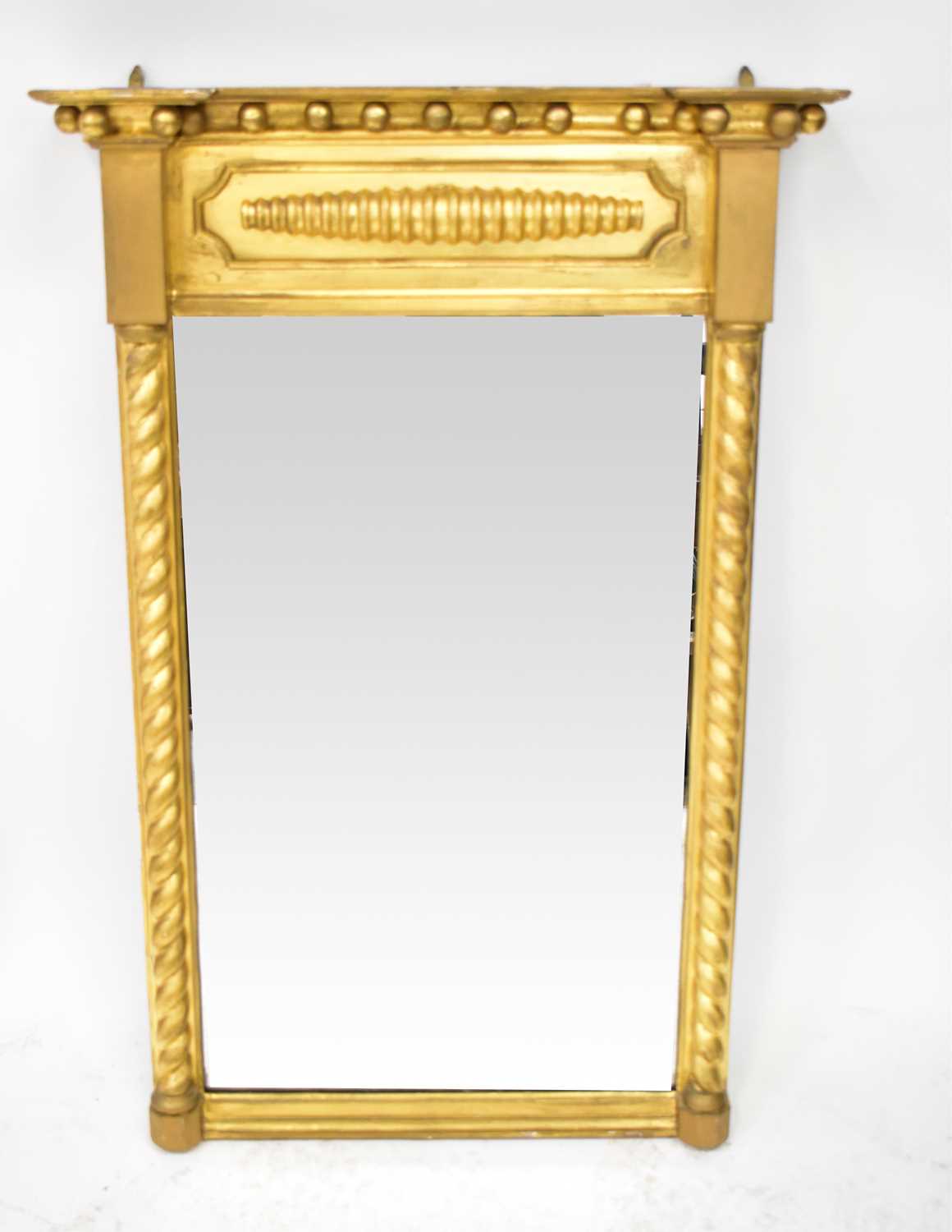 A 19th century gilt wood wall mirror with barleytwist pilasters, under a pediment with ball