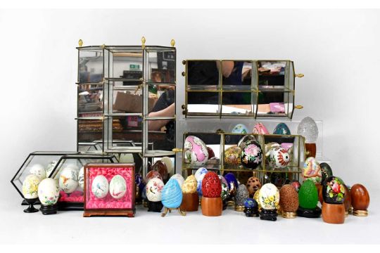 A collection of glass, ceramic, enamelled and painted eggs, together with three decorative stands (