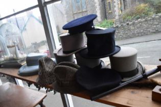A collection of vintage hats including top hats and transport cap.