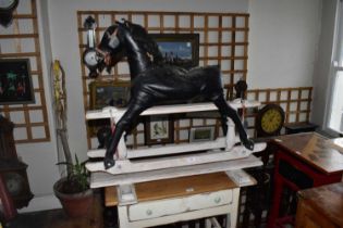 A vintage rocking horse, upholstered in a vinyl material on an associated painted pine base,