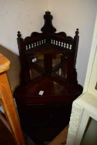 A late 19th century stained pine freestanding corner cupboard with glazed panels and carved doors,