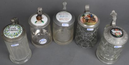 Fünf unterschiedliche Bierseidel. Deutsch um 1900. Farbloses Glas mit Zinndeckelmontur und Porzellan