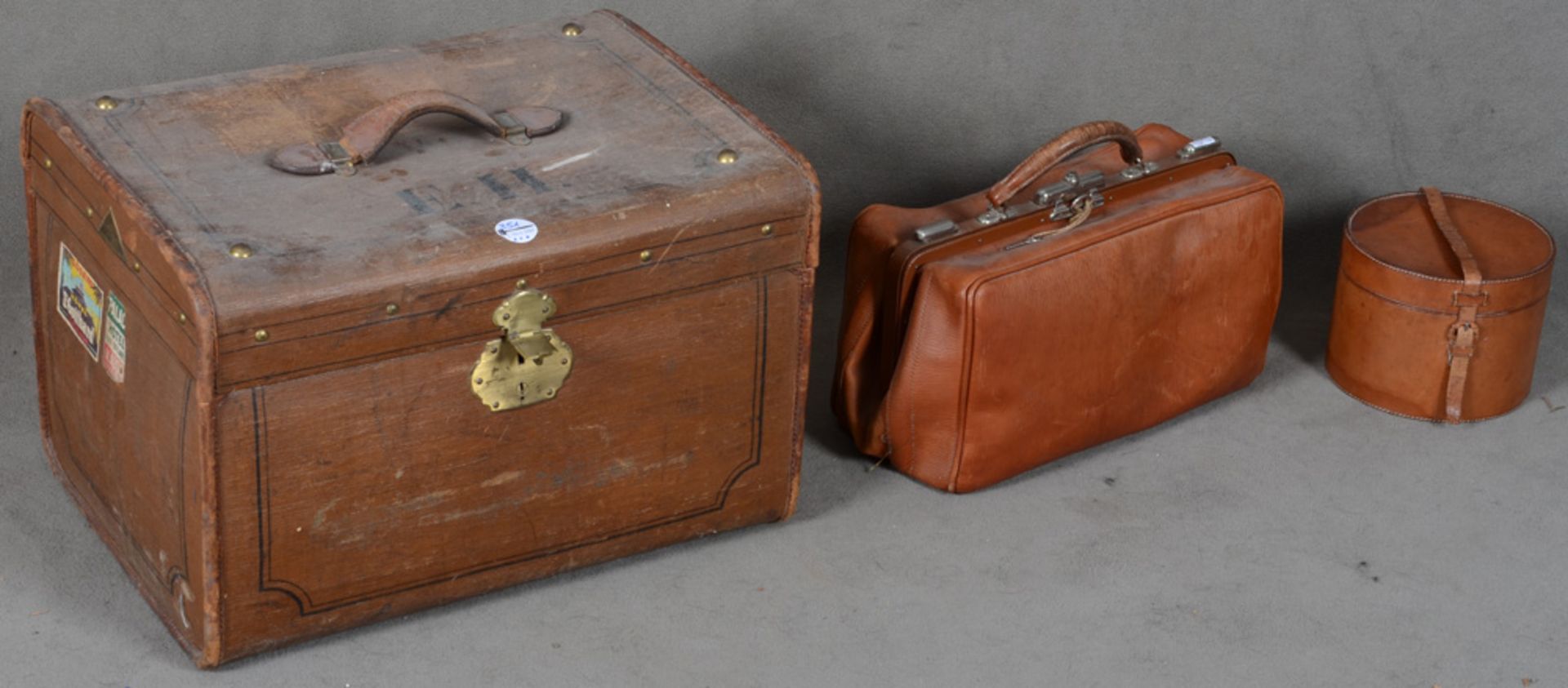 Eine Leder-Tasche mit Tragegriff, eine runde Leder-Hutschachtel sowie ein rechteckiger Koffer, H=
