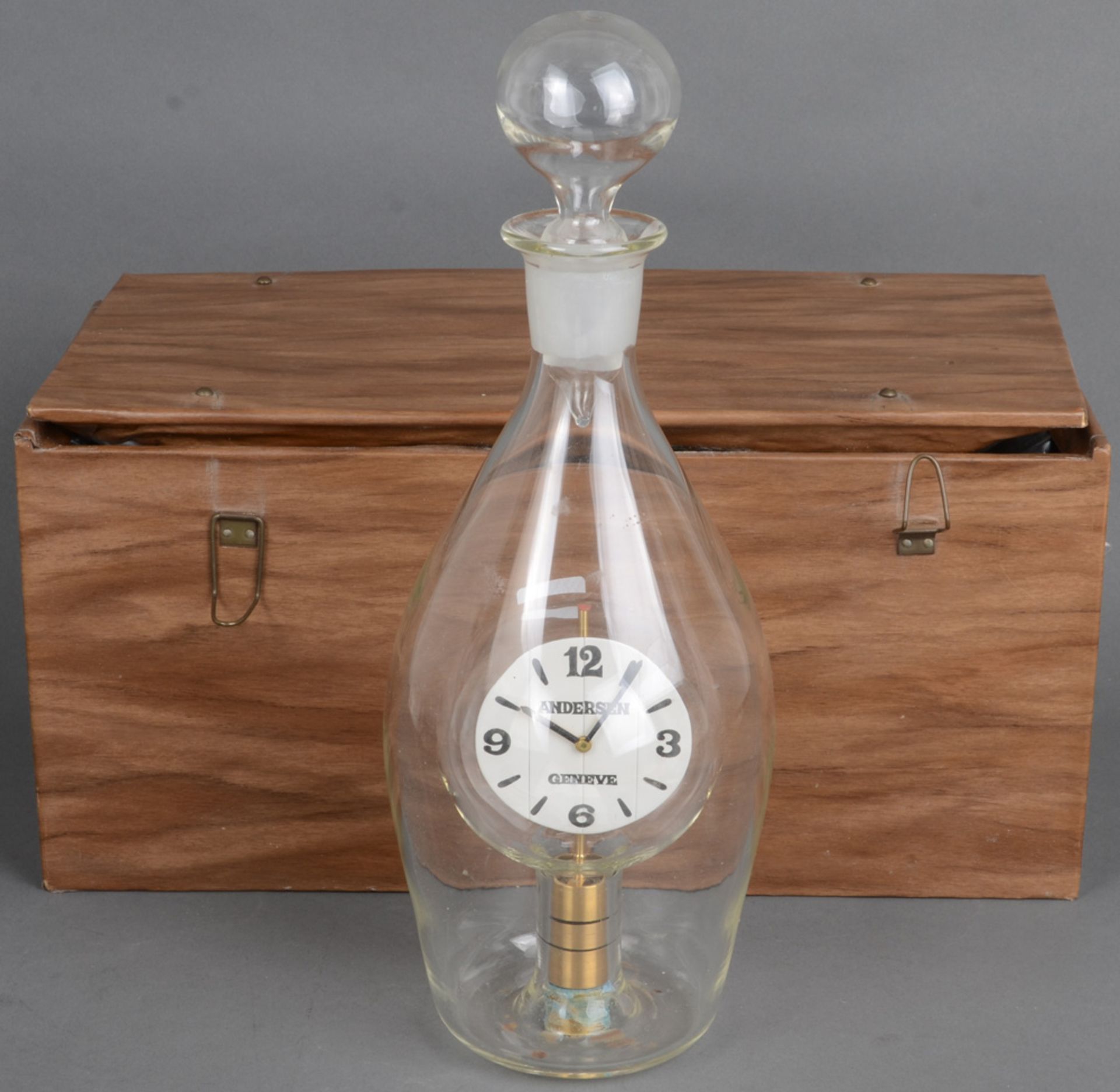 Flaschenuhr „Janus“. Genf, Meister Svend Andersen (*1942). Farbloses Glas, mit eingebauter Uhr; dazu