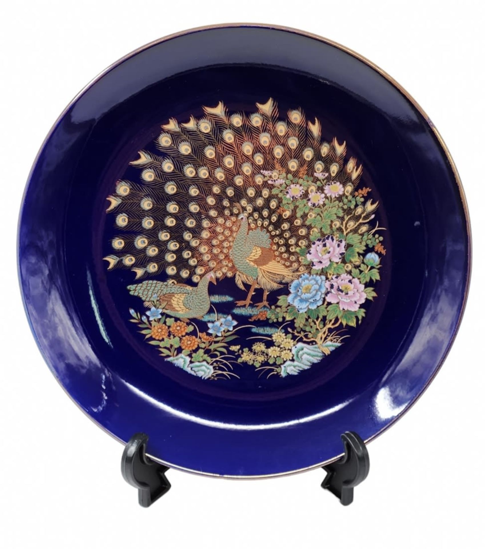 Round Japanese porcelain plate, decorated with a peacock pattern on a cobalt blue background.
