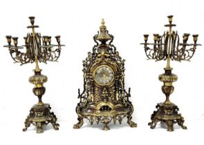 Antique Garniture, made of brass and includes a mantle clock and two candelabras, working