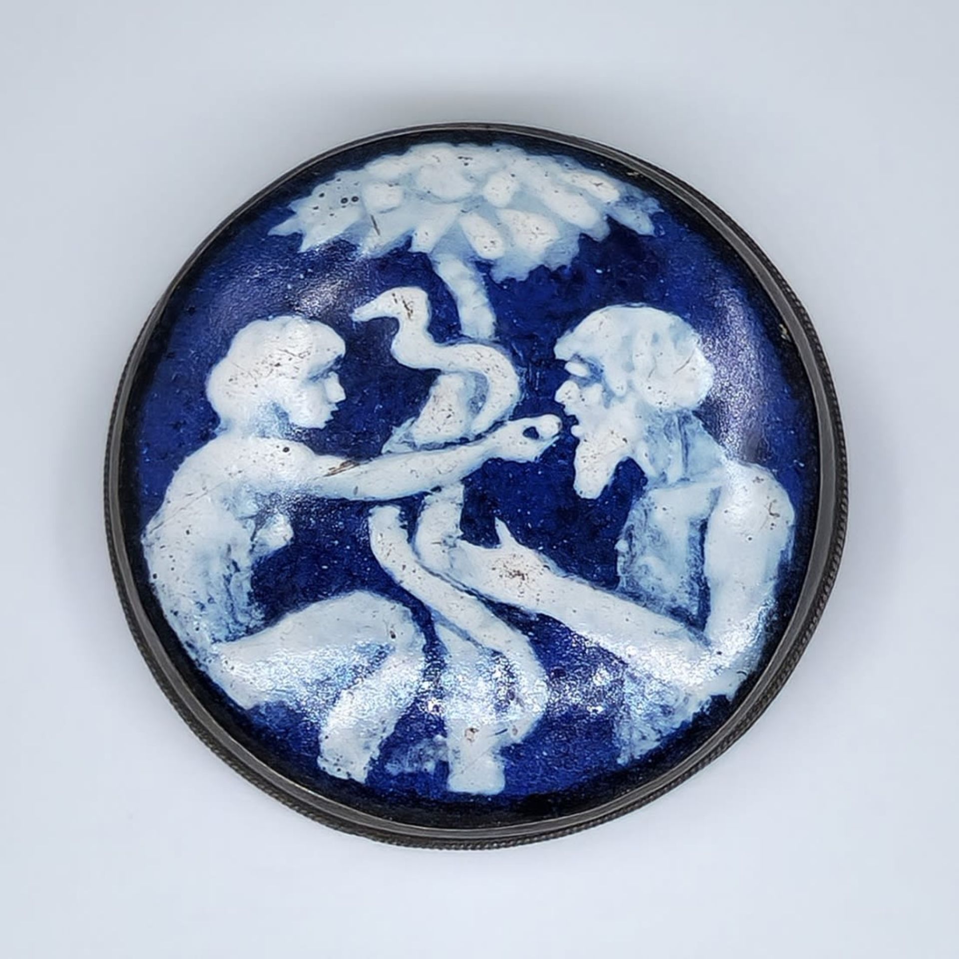 An enamel panel made by 'Bezalel', decorated with the image of Adam, Eve, and the snake next to