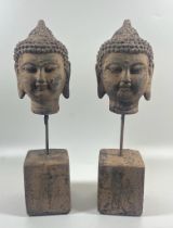 A PAIR OF DECORATIVE STONE BUDDHA HEADS ON PLINTHS, HEIGHT 30 CM