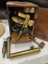 A VINTAGE BRASS MICROSCOPE IN AN OAK BOX WITH A DRAWER OF SLIDES AND TWO FURTHER FITMENTS