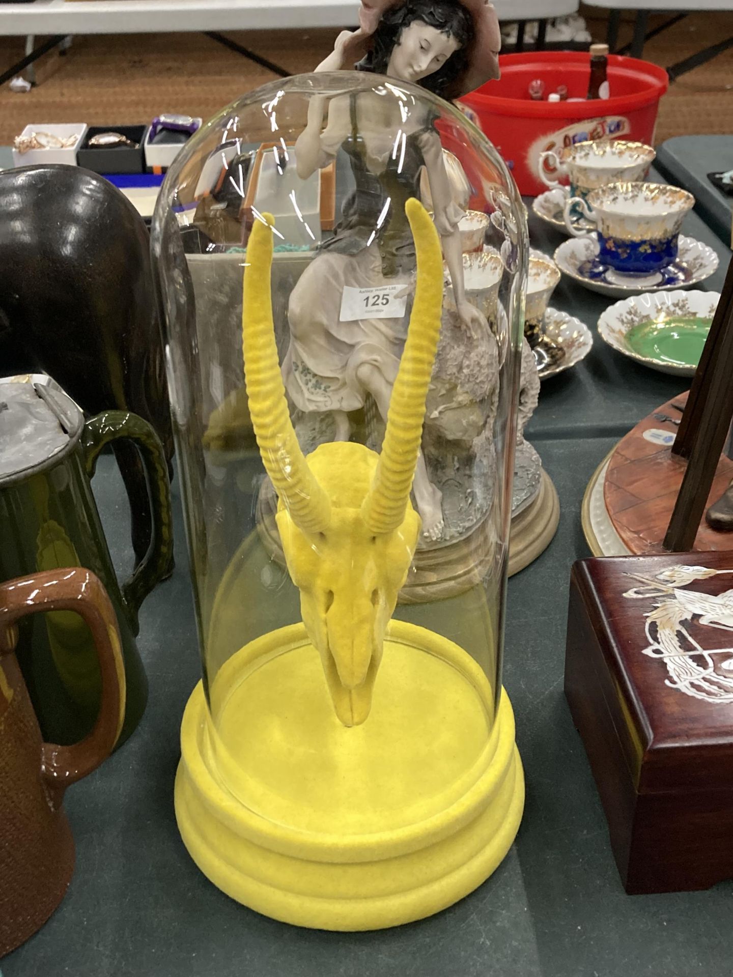 A YELLOW ANIMAL SKULL IN A GLASS DOME