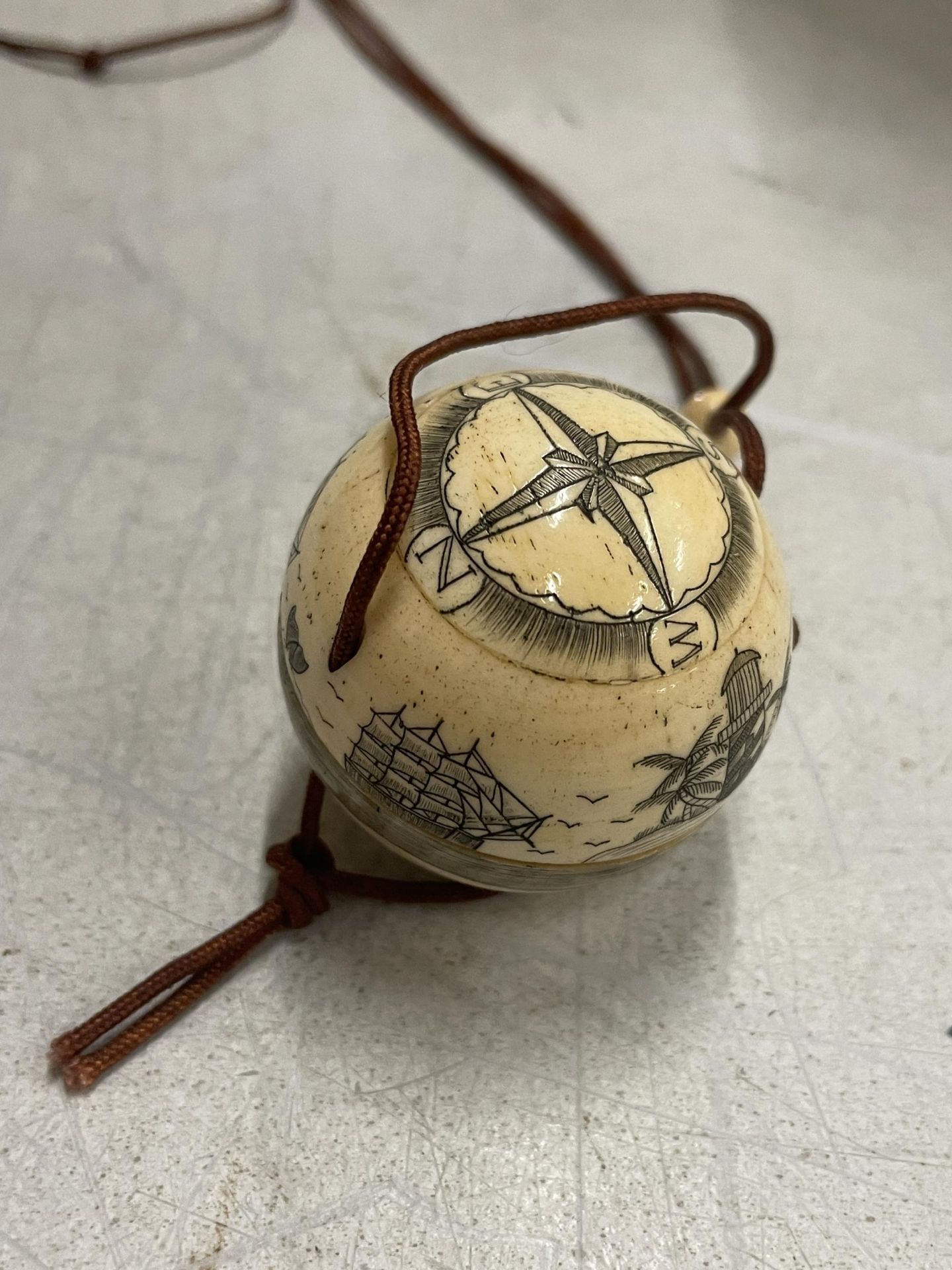 A BONE CARVED COMPASS ON A CORD
