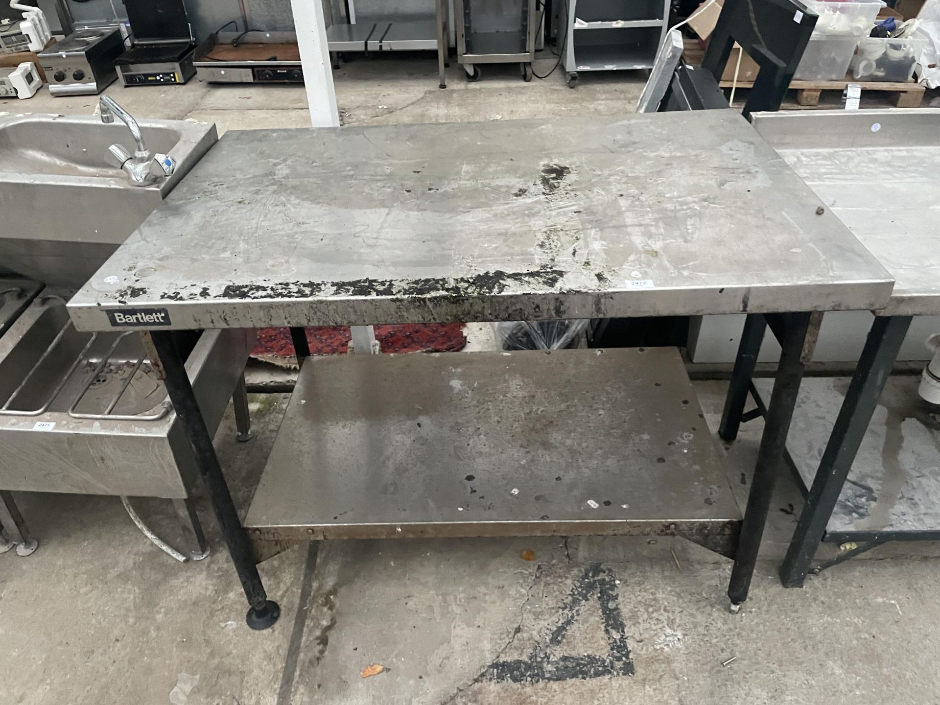 AN INDUSTRIAL STAINLESS STEEL TWO TIER KITCHEN WORK BENCH