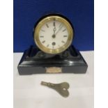 AN EBONISED CASED MANTLE CLOCK WITH 8 CM DIAL. HEIGHT 18CM AND KEY