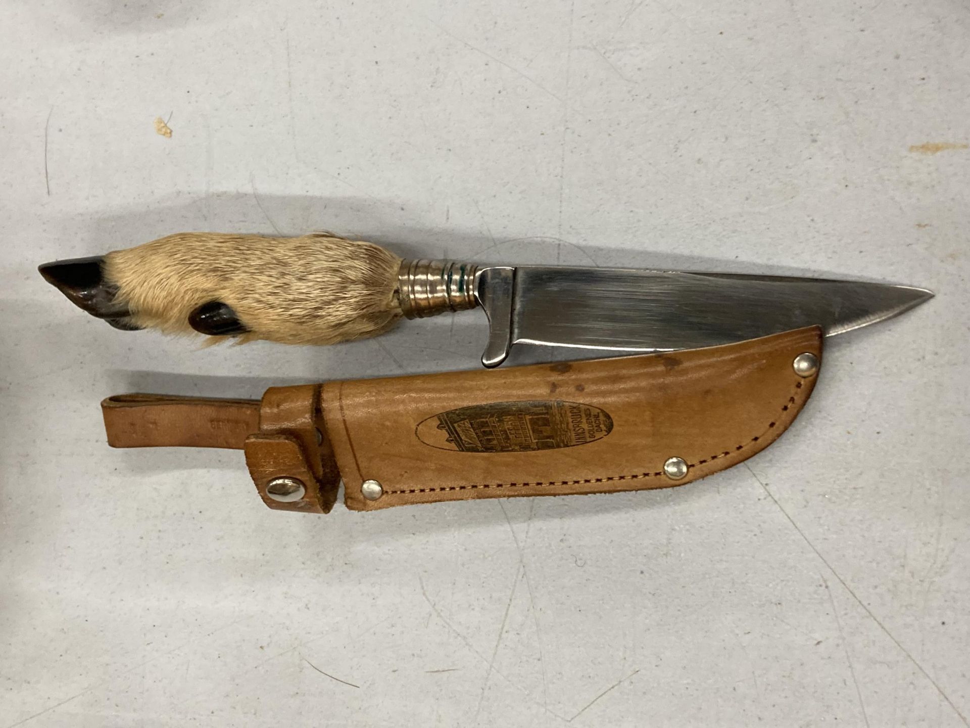 A HUNTING KNIFE WITH A DEER FOOT AHNDLE IN A LEATHER CASE