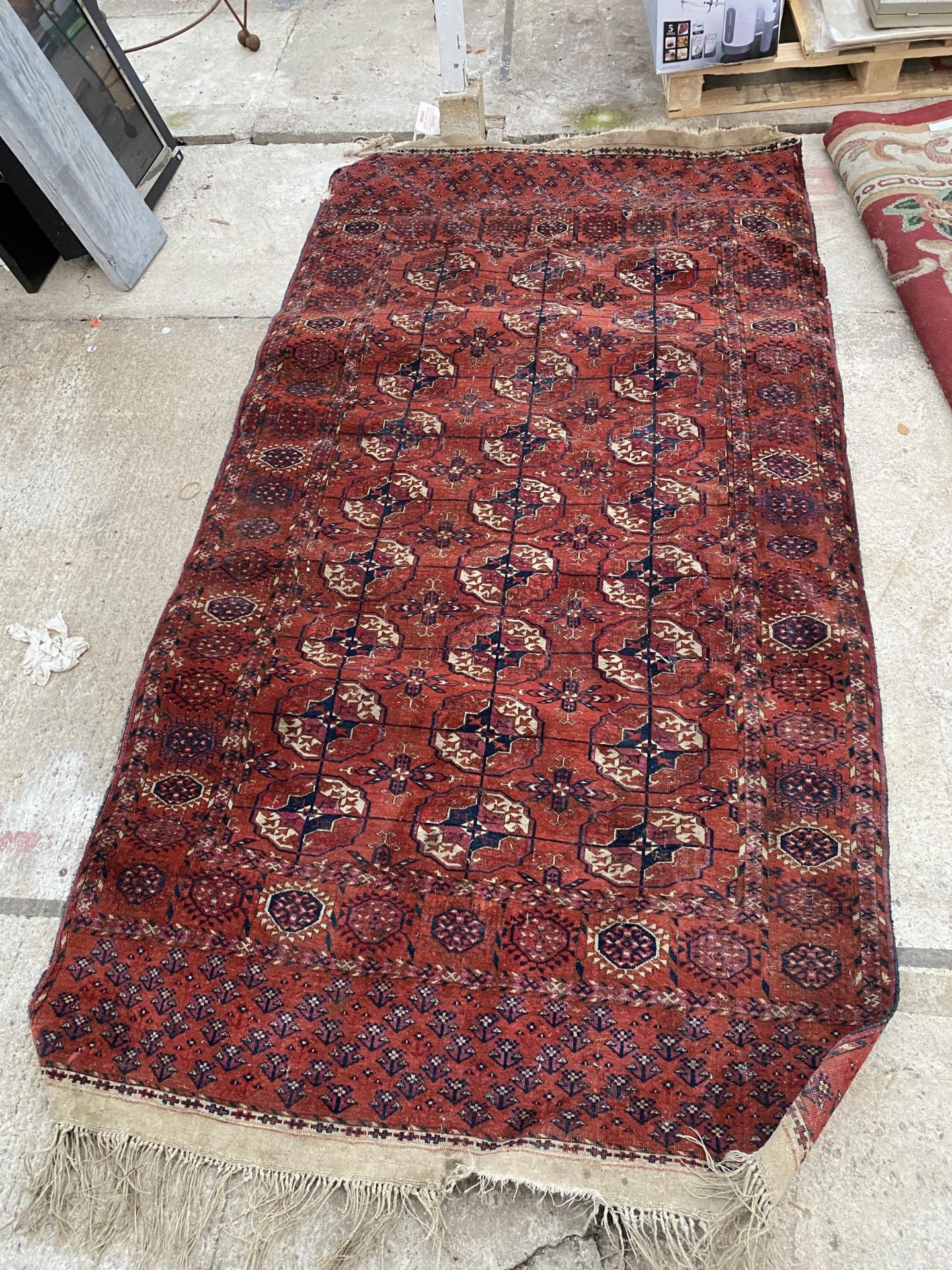 A VINTAGE RED PATTERNED FRINGED RUG