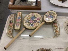 A VINTAGE PETIT-POINT BRUSH AND MIRROR SET ON A GLASS TRAY