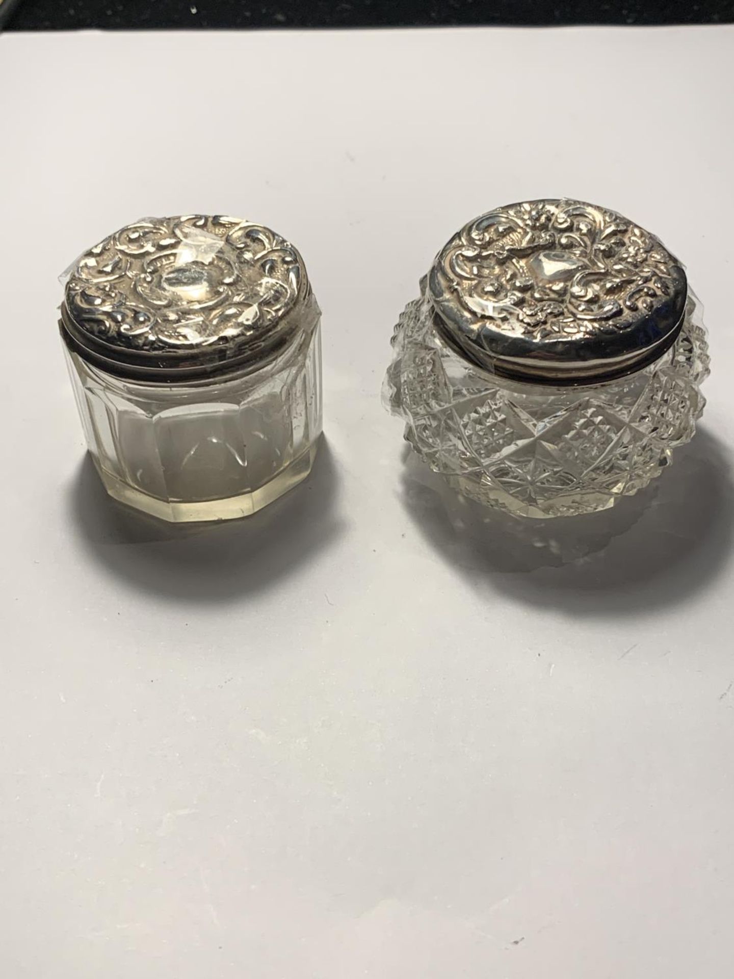 TWO GLASS JARS WITH ORNATE SILVER TOPS