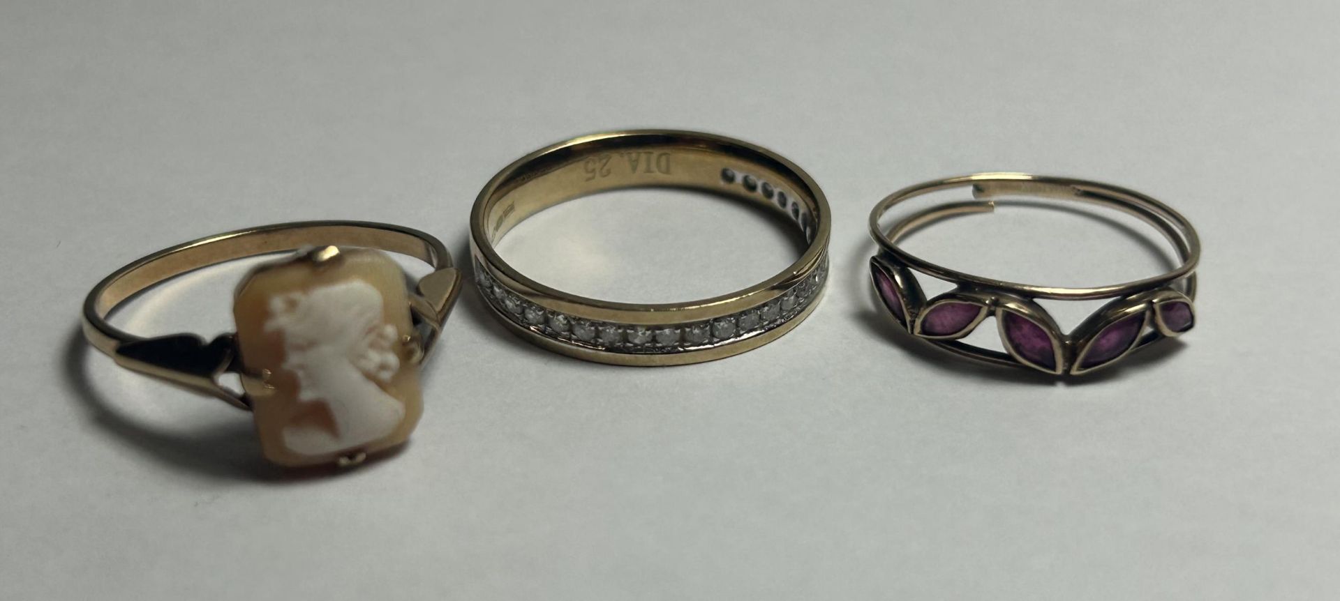THREE 9CT YELLOW GOLD RINGS TO INCLUDE A CAMEO RING, A DIAMOND HALF ETERNITY RING AND A GARNET RING