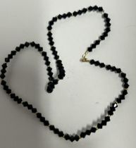 AN 18CT GOLD CLASPED BLACK FACET STONE NECKLACE, LENGTH 40CM