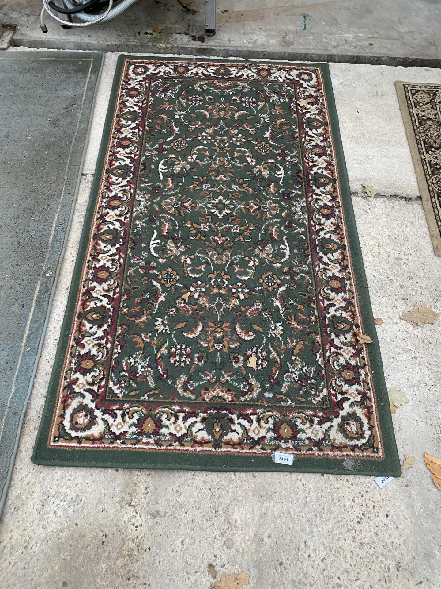 A SMALL GREEN PATTERNED RUG