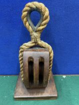 A VINTAGE WOOD AND ROPE PULLEY
