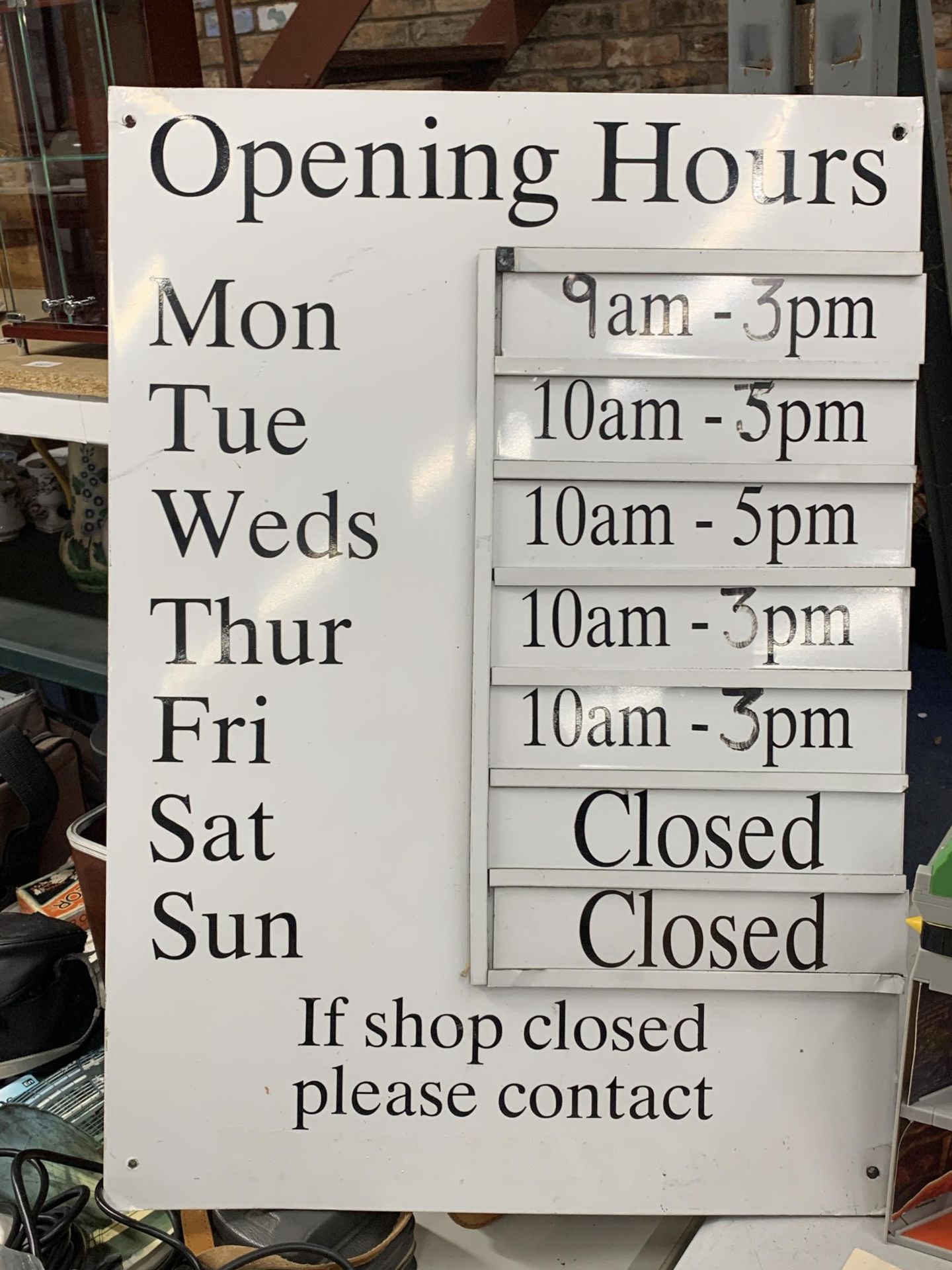 A METAL SHOP OPENING HOURS SIGN WITH INTERCHANGEABLE TIME SLIDES