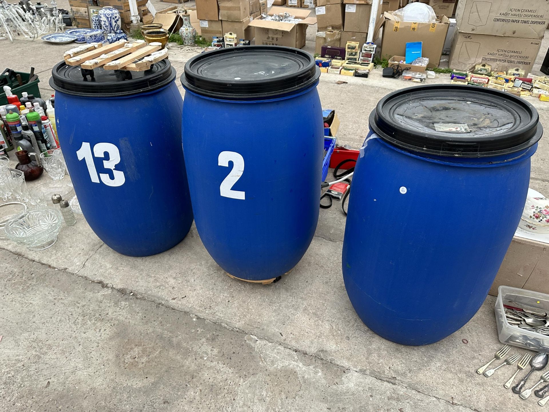 THREE LIDDED PLASTIC DRUMS TWO WITH TROLLEY BASES