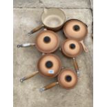 A SET OF SIX GRADUATED RETRO BROWN LE CREUSET PANS