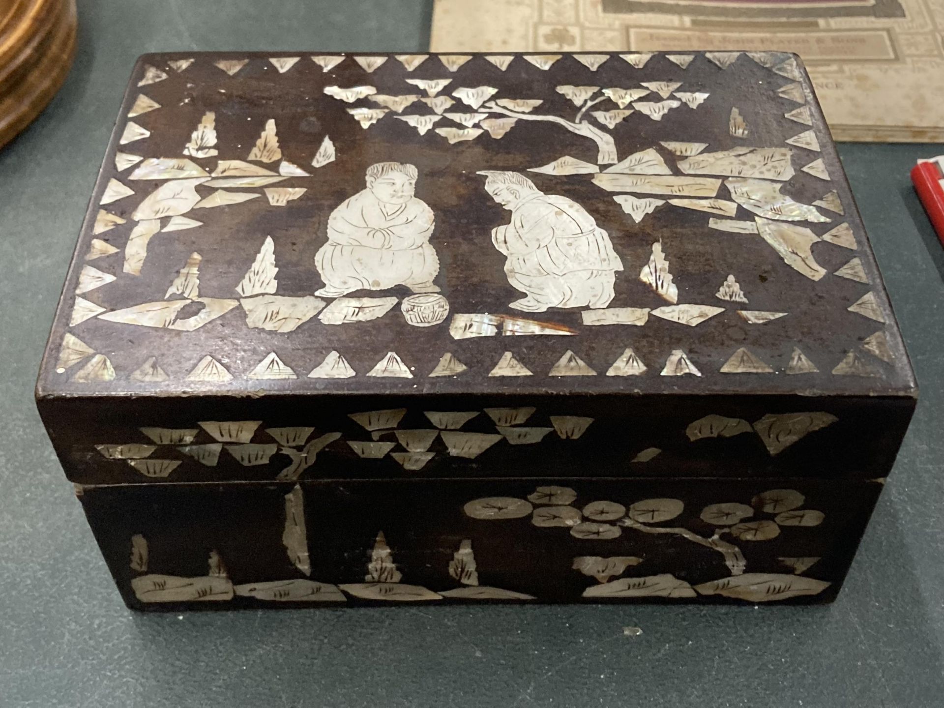 A MOTHER OF PEARL INLAID WOODEN BOX WITH ORIENTAL SCENE TO THE LID