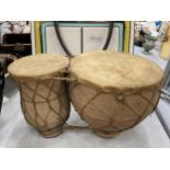 A SET OF TWO ANIMAL HIDE AFRICAN DRUMS