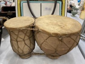 A SET OF TWO ANIMAL HIDE AFRICAN DRUMS