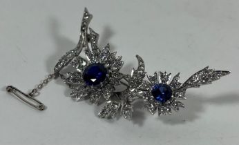 A SILVER ART DECO SAPPHIRE STYLE BLUE AND CLEAR STONE FLORAL BROOCH