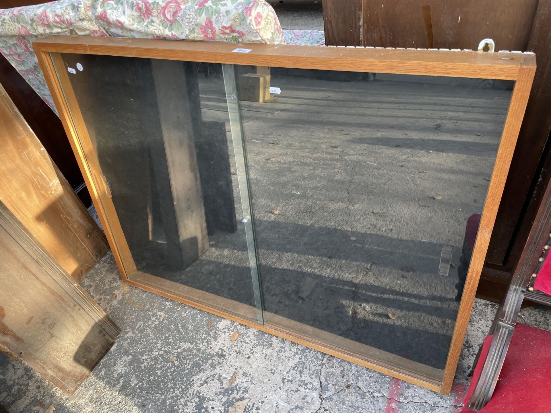AN OAK FRAMED GLASS FRONTED WALL CABINET