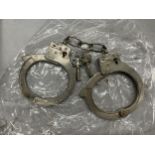 A PAIR OF HANDCUFFS WITH KEYS